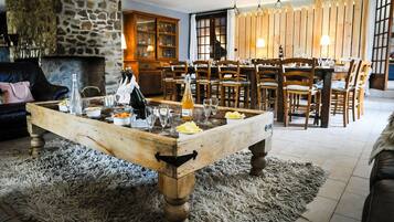 A cozy living room with a stone fireplace, wooden dining table, and a plush rug.