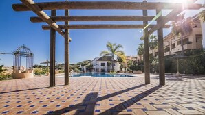 Een zwembadgedeelte met een pergola, een helderblauwe lucht en een gebouw op de achtergrond.