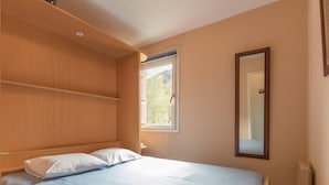 A bedroom with a bed, a window, and a mirror.
