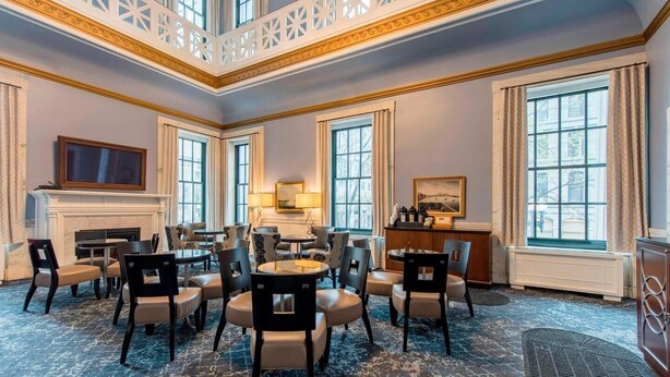 A spacious hotel lobby with a central seating area, large windows, and a fireplace.