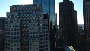A cityscape with modern high-rise buildings, including a distinctive building with a unique facade and another with a glass exterior.