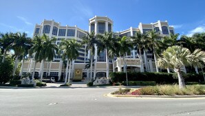 A large hotel with multiple floors, palm trees in the foreground, and a clear blue sky. - Marco Beach Ocean Resort 610: Private 1 Bedroom condo; New Tile,TV's (Marco Island)