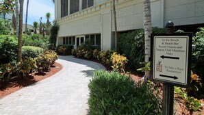 A pathway leading to a building with a sign indicating directions to the beach, beach bar, resort guests, and Tarpon Club members. - Marco Beach Ocean Resort 610: Private 1 Bedroom condo; New Tile,TV's (Marco Island)