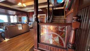 A spacious living area with a large wooden staircase, a fireplace with stained glass, and a cozy seating area with a sofa and armchairs. - Absolutely fantastic, charming retreat with ocean views! (Seaside)