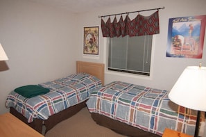A room with two beds, a window with blinds, a lamp, and two posters on the wall. - Beaver Ridge 260 (Davis)