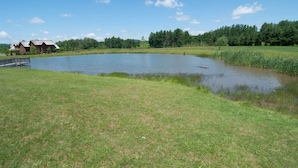A serene lakeside setting with a wooden dock, a small building, and lush greenery. - Aspen Village 35 (Davis)