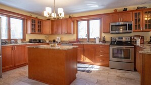 Un'ampia cucina con mobili in legno, un'isola centrale, un forno a microonde integrato e un forno in acciaio inossidabile.