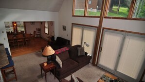 A spacious living room with a brown sofa, a coffee table, and a lamp. There is a dining area in the background with wooden chairs and a table. - Bear`s Den - Northface (Davis)