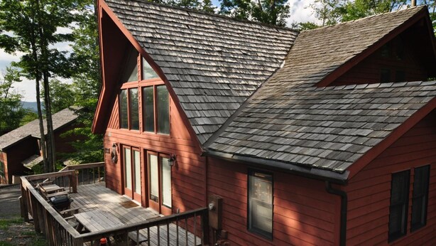 A red wooden cabin with a sloped roof, a deck, and a small porch. - Bear`s Den - Northface (Davis)