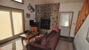A cozy living room with a stone fireplace, a television, and a sofa. - Bear`s Den - Northface (Davis)