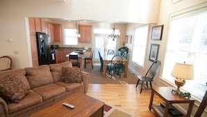 A living room with a sofa, coffee table, and a dining area with chairs and a table.