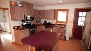 A compact kitchen with wooden cabinets, a central island, and basic appliances. - Almost Heaven (Davis)