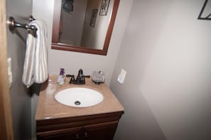Un baño con un lavamanos blanco, un espejo y un perchero para toallas.