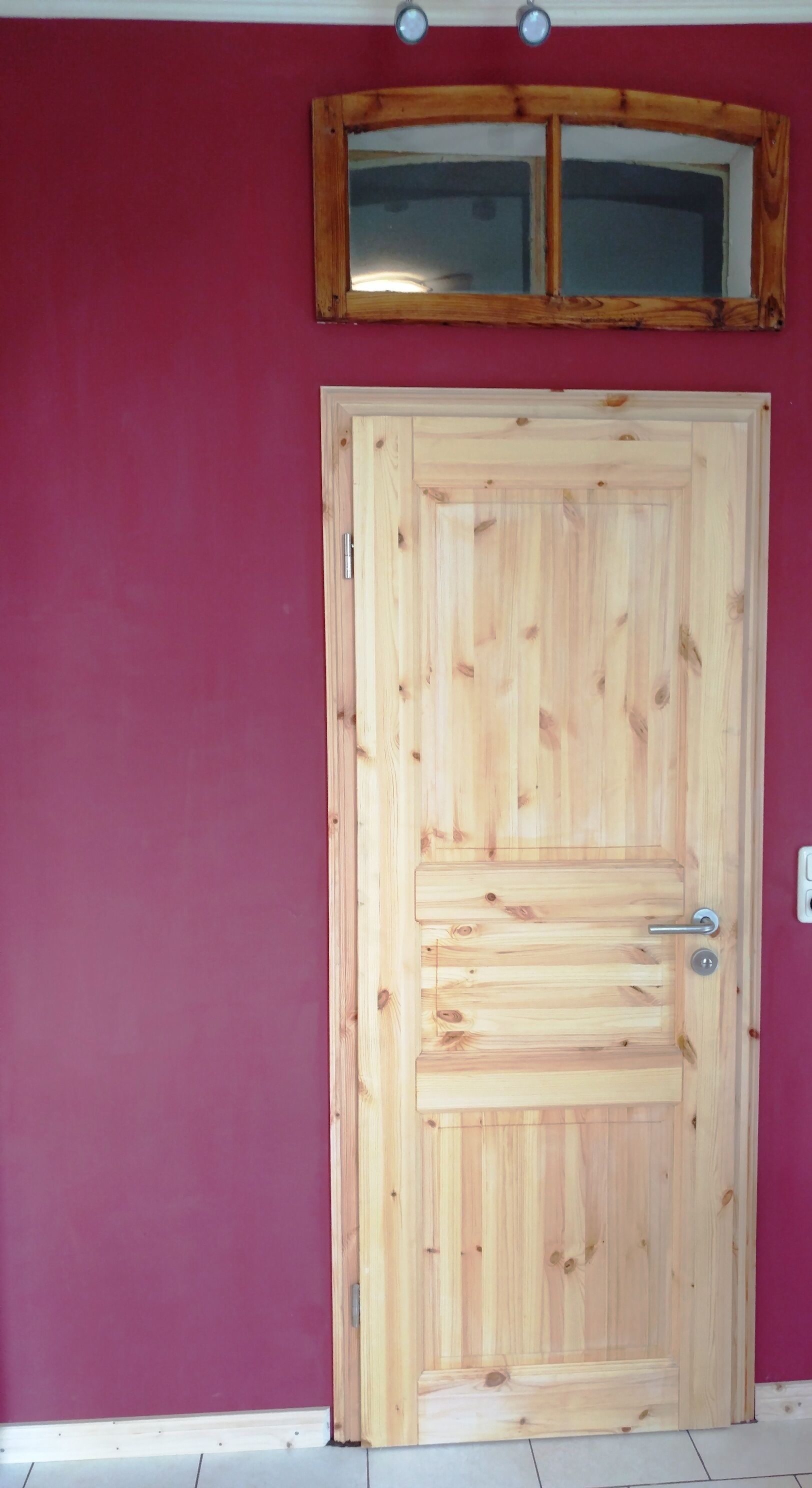 A wooden door with a metal handle and a small window above it.