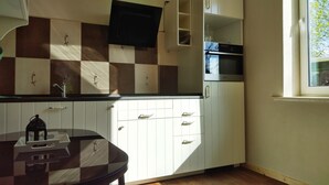 Una cocina con armarios blancos, encimera negra y ventana.