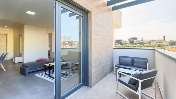 Ein modernes Apartment mit Balkon, einer Couch, einem Esstisch und einem Stuhl.