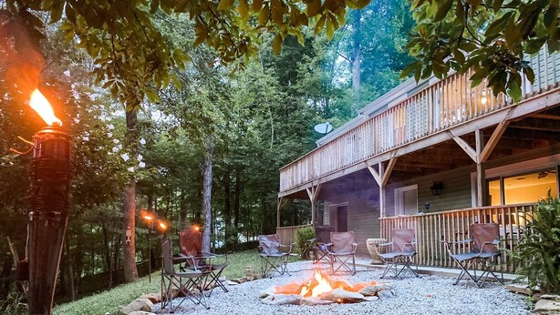 A rustic outdoor seating area with a fire pit, surrounded by rocks and wooden furniture.