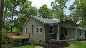 A two-story house with a covered porch, a small deck, and a landscaped front yard.