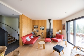 Una sala de estar moderna con chimenea, sofás rojos y una escalera.