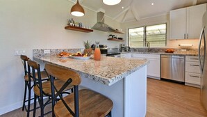A modern kitchen with a central island, bar stools, pendant lighting, and stainless steel appliances.