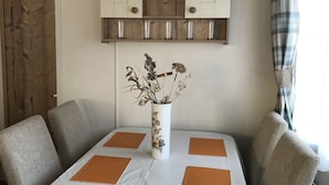 A dining table with four chairs, a vase with dried flowers, and a pendant light above. - Cairngorms Flower Lodge (Aviemore)