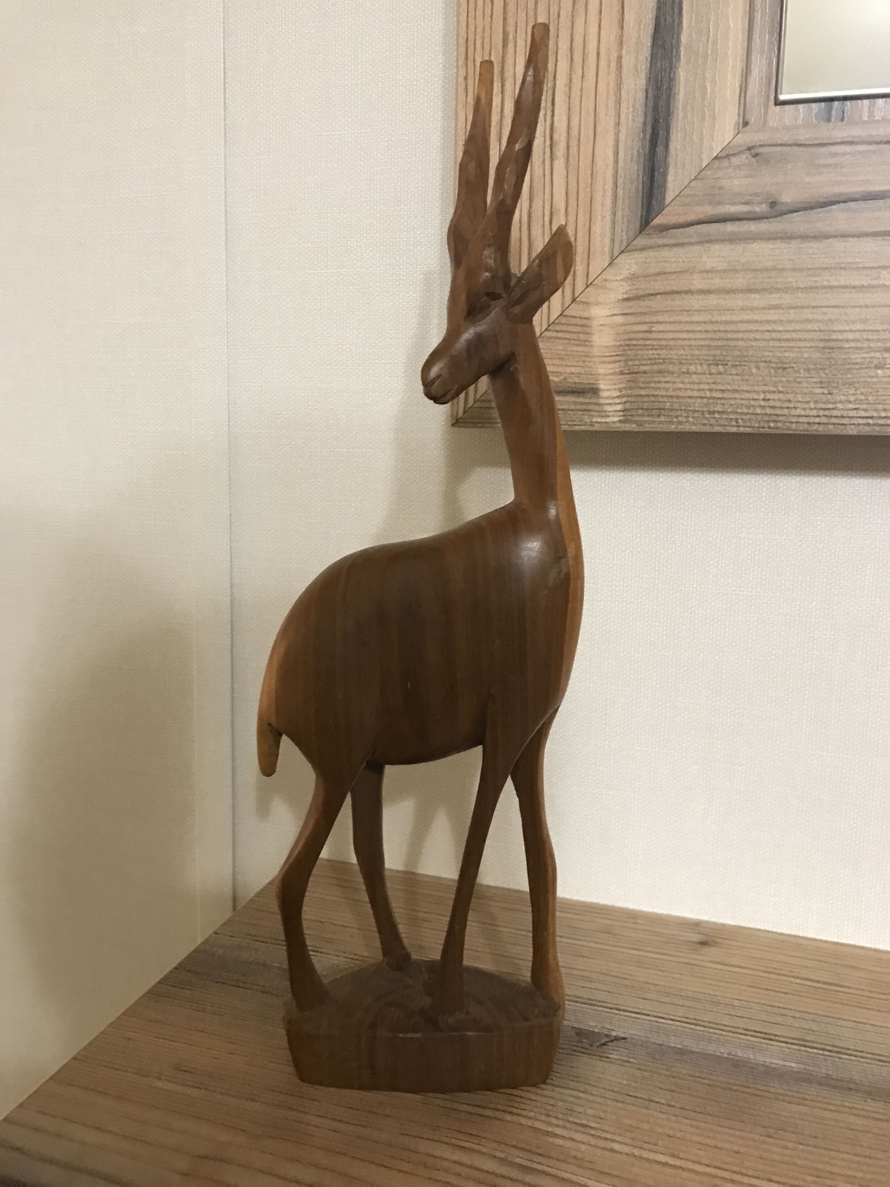 A wooden deer sculpture on a wooden base.