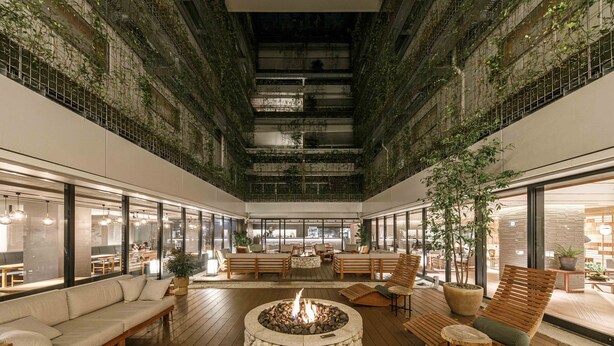 Un vaste atrium intérieur doté d’un foyer central, de coins salon et offrant une vue sur l’extérieur du bâtiment.