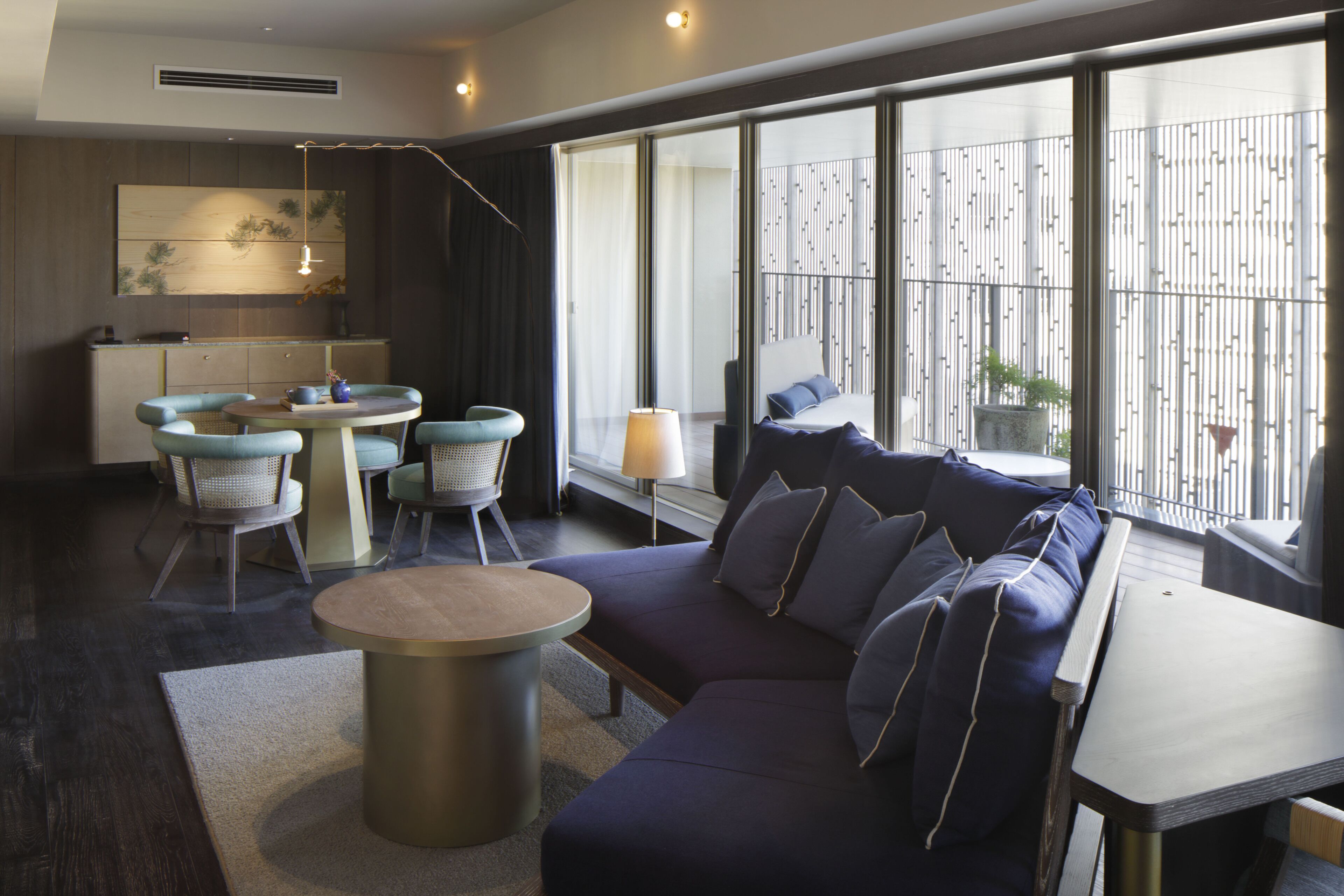 A modern living room with a sofa, a round table, and a dining area with chairs.