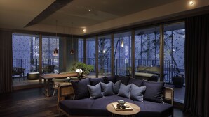 Un salon moderne avec un canapé bleu foncé, une table basse ronde et un coin repas comprenant une table et des chaises en bois.