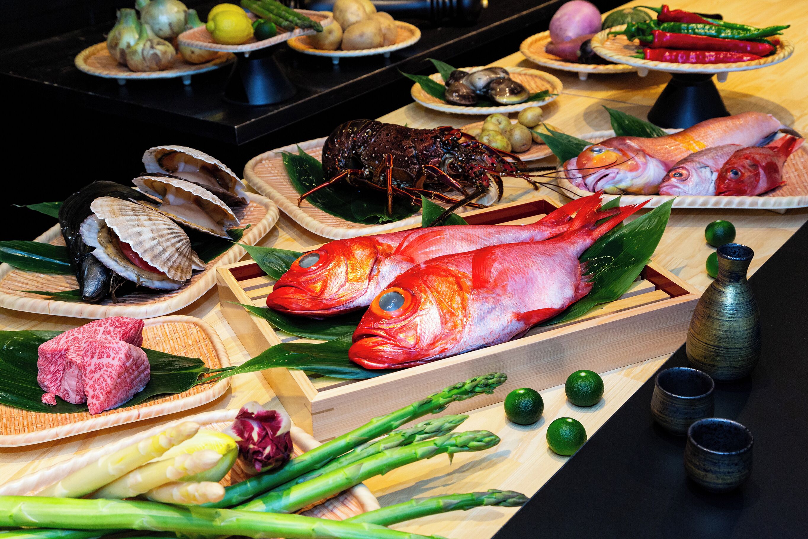Verschiedene Meeresfrüchte, darunter Hummer, Fisch und Venusmuscheln, auf Holztabletts.