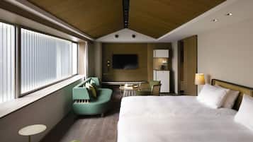 A hotel room with a large bed, a sofa, a small table, and a TV mounted on the wall.