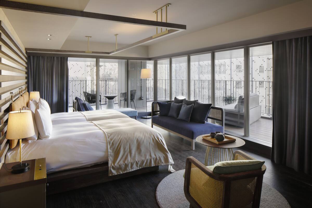 Ein modernes Hotelzimmer mit einem großen Bett, einer Couch, einem kleinen Tisch und einem Balkon mit Blick.