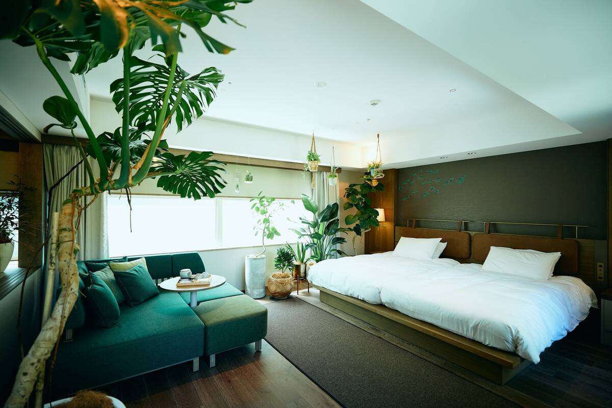 Ein modernes Schlafzimmer mit einem großen Bett, einem grünen Sofa und einem kleinen runden Tisch.