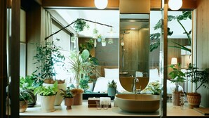 Une salle de bain avec un grand miroir, un lavabo rond et diverses plantes en pot.