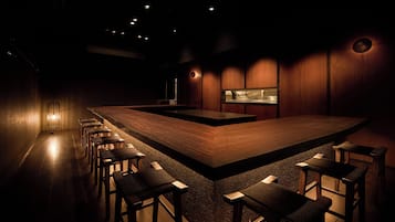 A dimly lit bar area with a long counter and several stools.