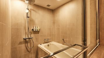 Ein modernes Badezimmer mit Duschkabine aus Glas, einer Badewanne mit Glastrennwand und beigefarbenen Fliesen.
