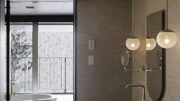 Un baño moderno con una bañera independiente, dos lavabos y un espejo grande.