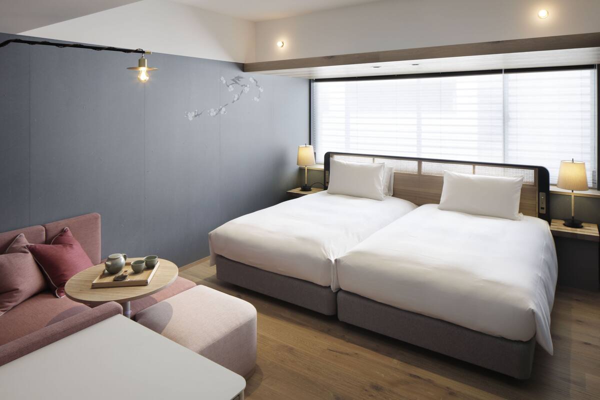 Ein modernes Hotelzimmer mit einem großen Bett, einer Couch und einem kleinen Tisch mit einer Teetassebene.