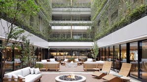 Un vaste patio intérieur doté d’un foyer, de coins salon et offrant une vue sur l’intérieur du bâtiment.