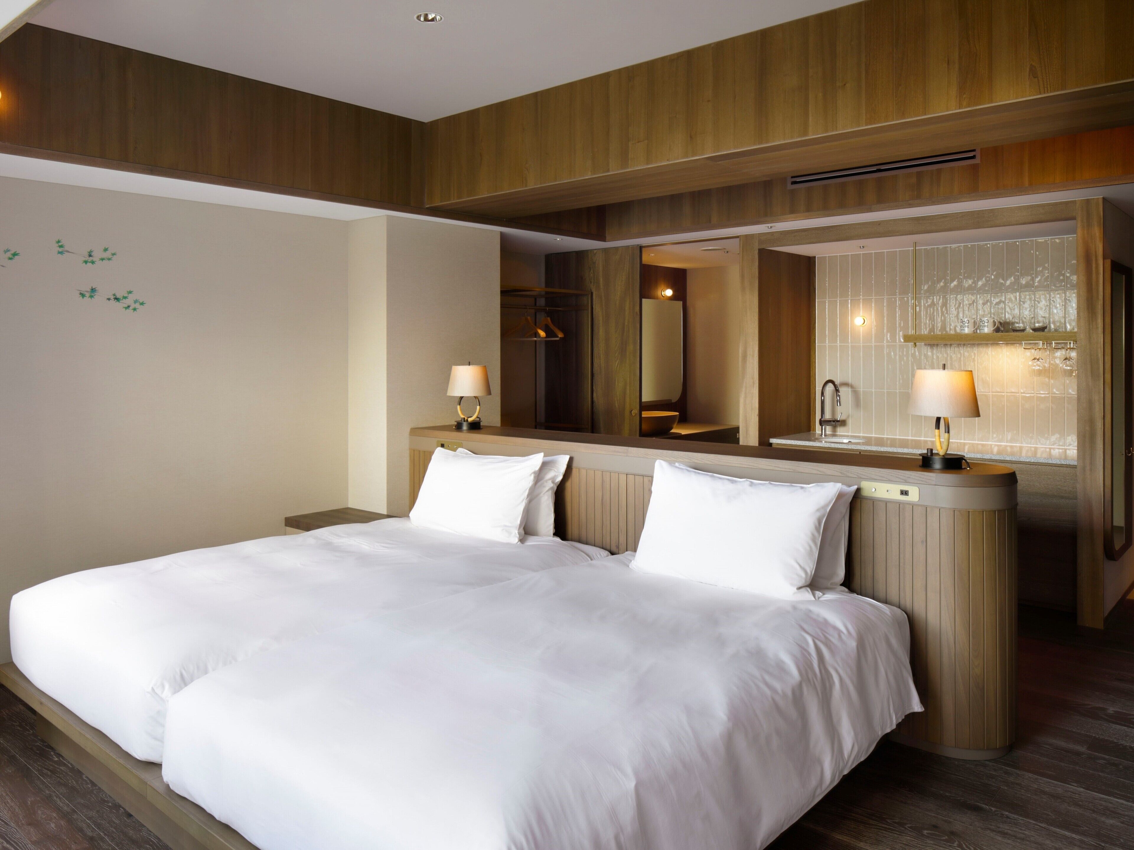 Een hotelkamer met een groot bed, een houten hoofdeinde, een spiegel en een klein badgedeelte.