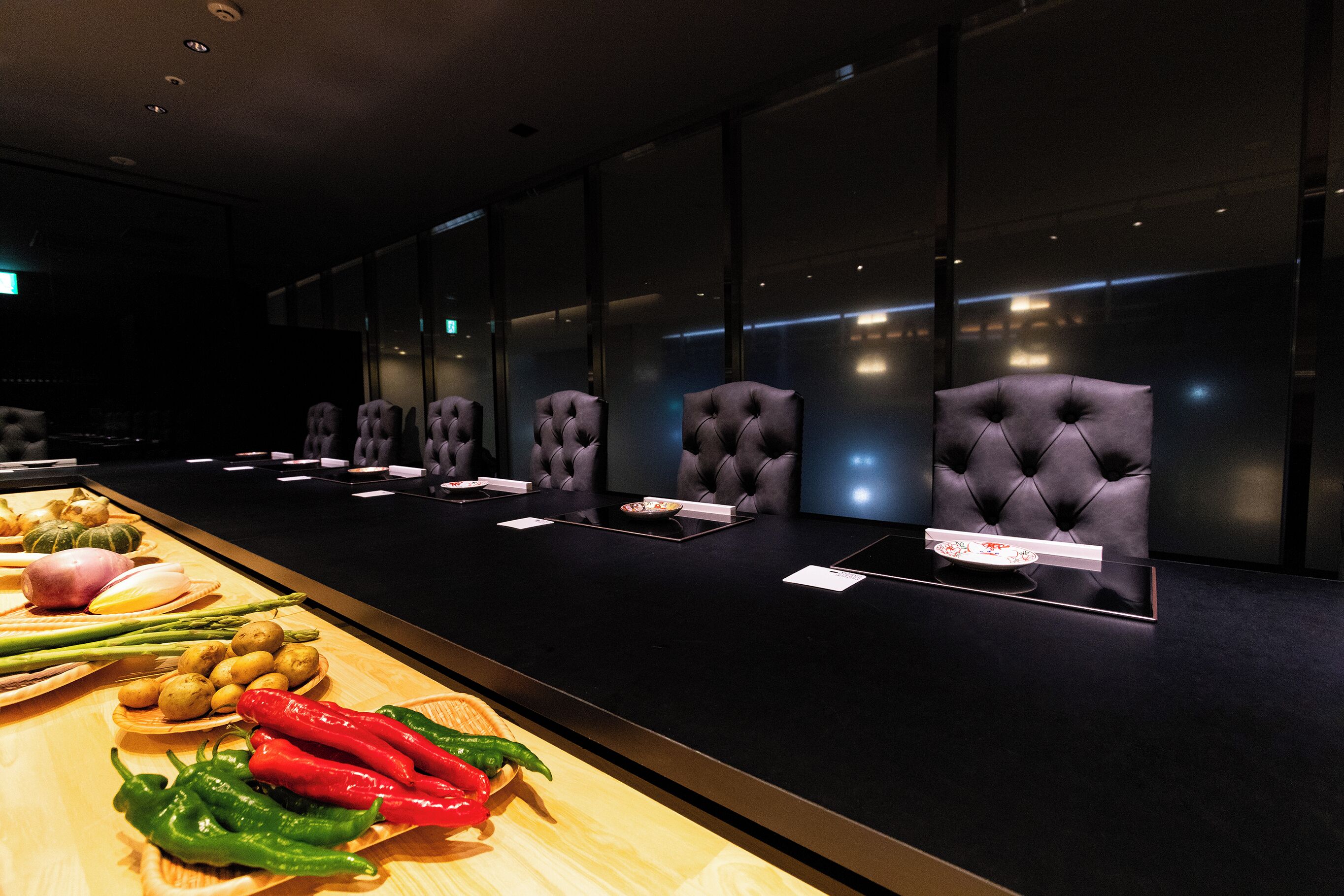A conference room with a long table, multiple chairs, and a display of vegetables.