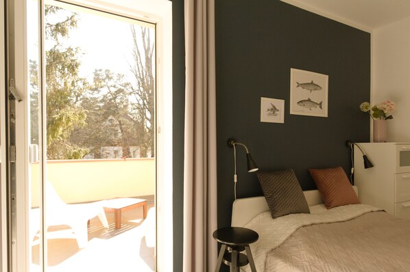 A bedroom with a bed, a nightstand, a lamp, and a window with curtains. - 4 rooms, south-facing terrace, 3 kitchens, 3 bathrooms, promenade nearby (Swinemünde)