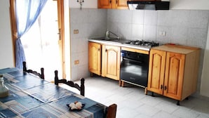Una cocina con gabinetes de madera, estufa a gas y salpicadero de azulejos.