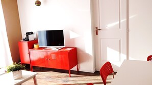 Ein Zimmer mit einem roten Schrank, einem Fernseher, einer weißen Tür und einem roten Sessel.