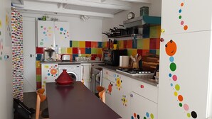 Eine Küche mit bunten Fliesen, einem roten Topf, einem Toaster und einer Waschmaschine.