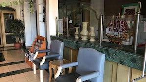 A reception area with a counter, two armchairs, a small round table, and a potted plant. - The Executive Hotel Lahad Datu (Lahad Datu)