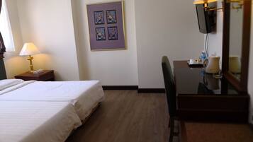 A hotel room with two beds, a desk with a chair, a television, and a framed artwork on the wall.