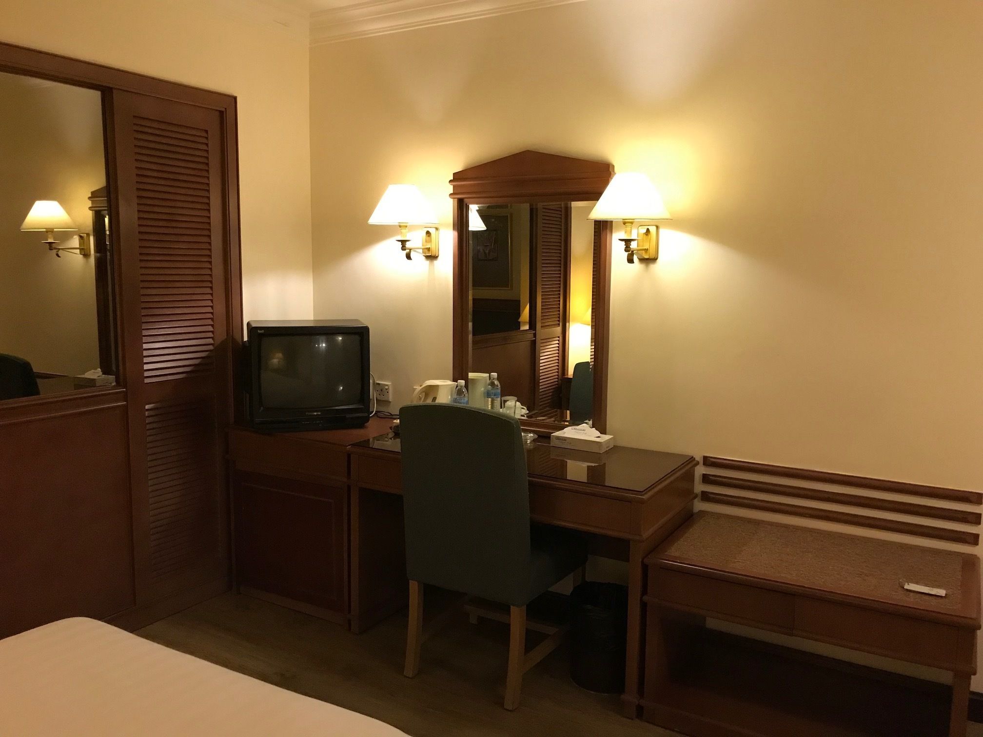 A hotel room with a desk, chair, television, and a bed.