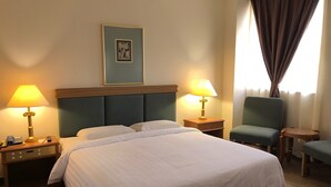 A hotel room with a large bed, two bedside tables with lamps, a chair, and a framed picture on the wall. - The Executive Hotel Lahad Datu (Lahad Datu)