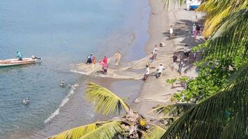 A beach with people fishing and a boat on the water.